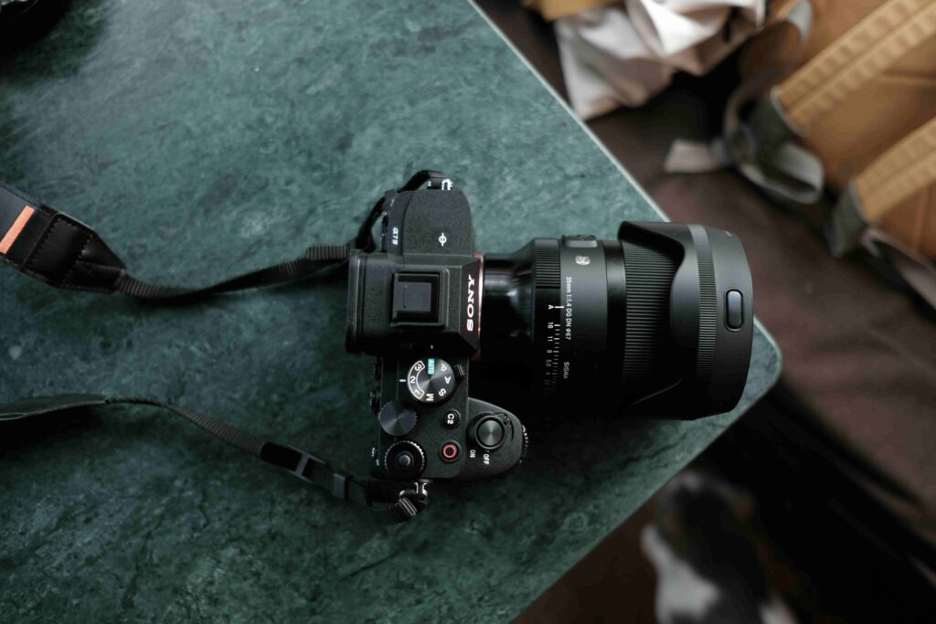An overhead photo of a small and compact Sony DSLR camera, on the edge of a teal countertop.