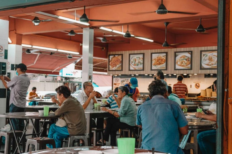 An image of a Hawker food center filled with locals having their lunch as they feast of Singapore's delicacies.