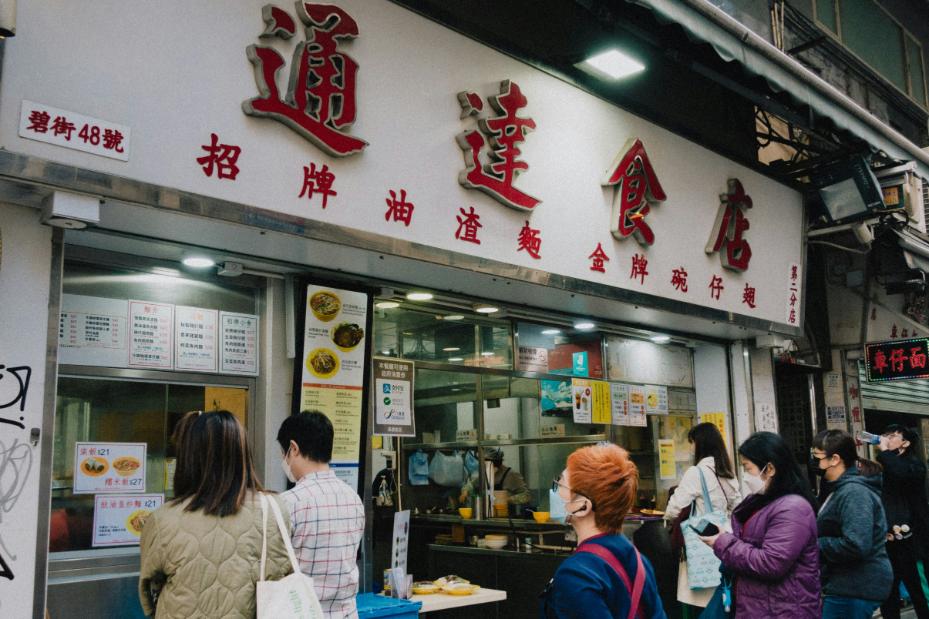 A photo of a Hawker stall during the afternoon with people lining up to order or to claim their meals.