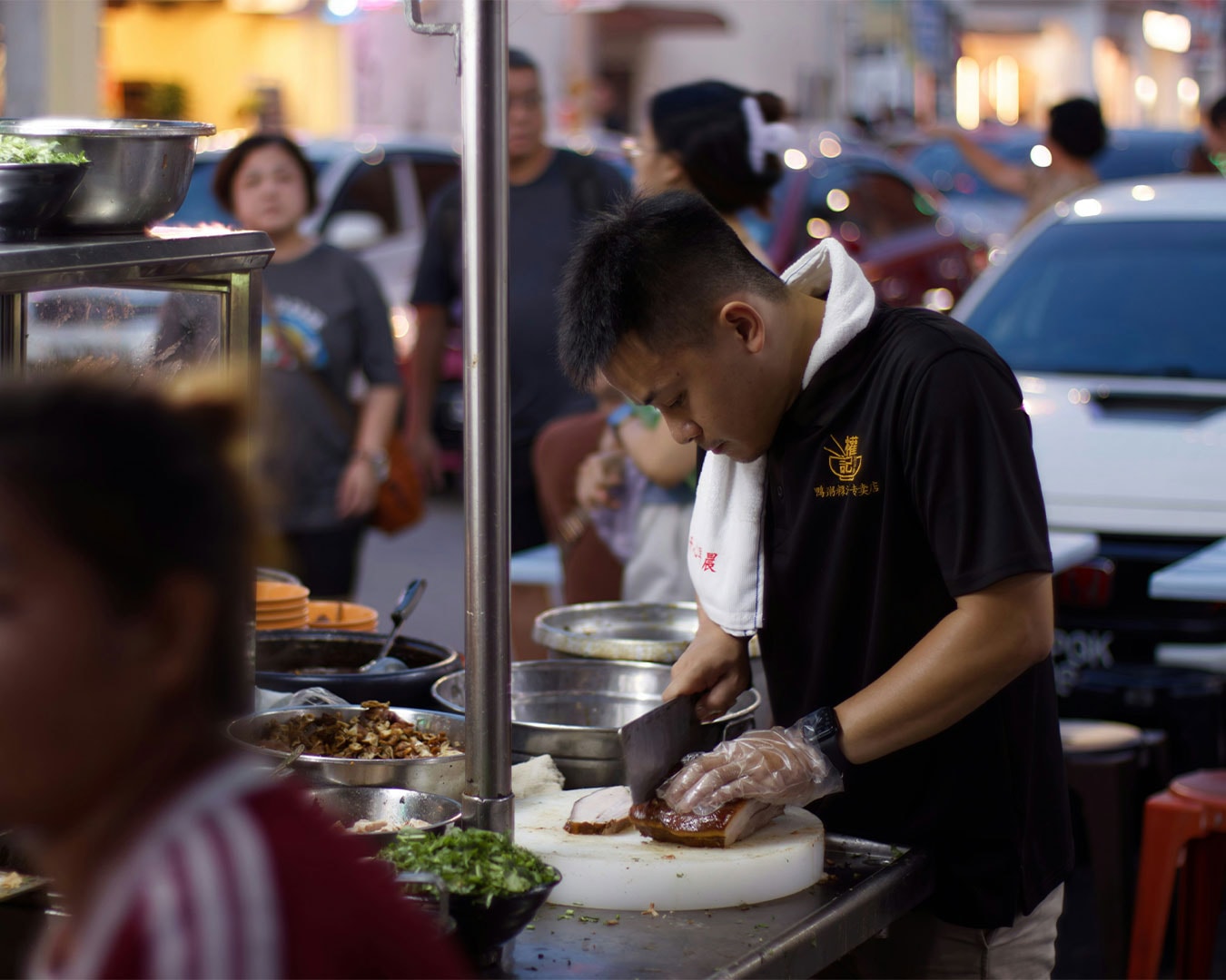 A street food vendor chops chicken on a wooden board at his roadside stall, showing the fast-paced preparation behind everyday meals in the local food scene.