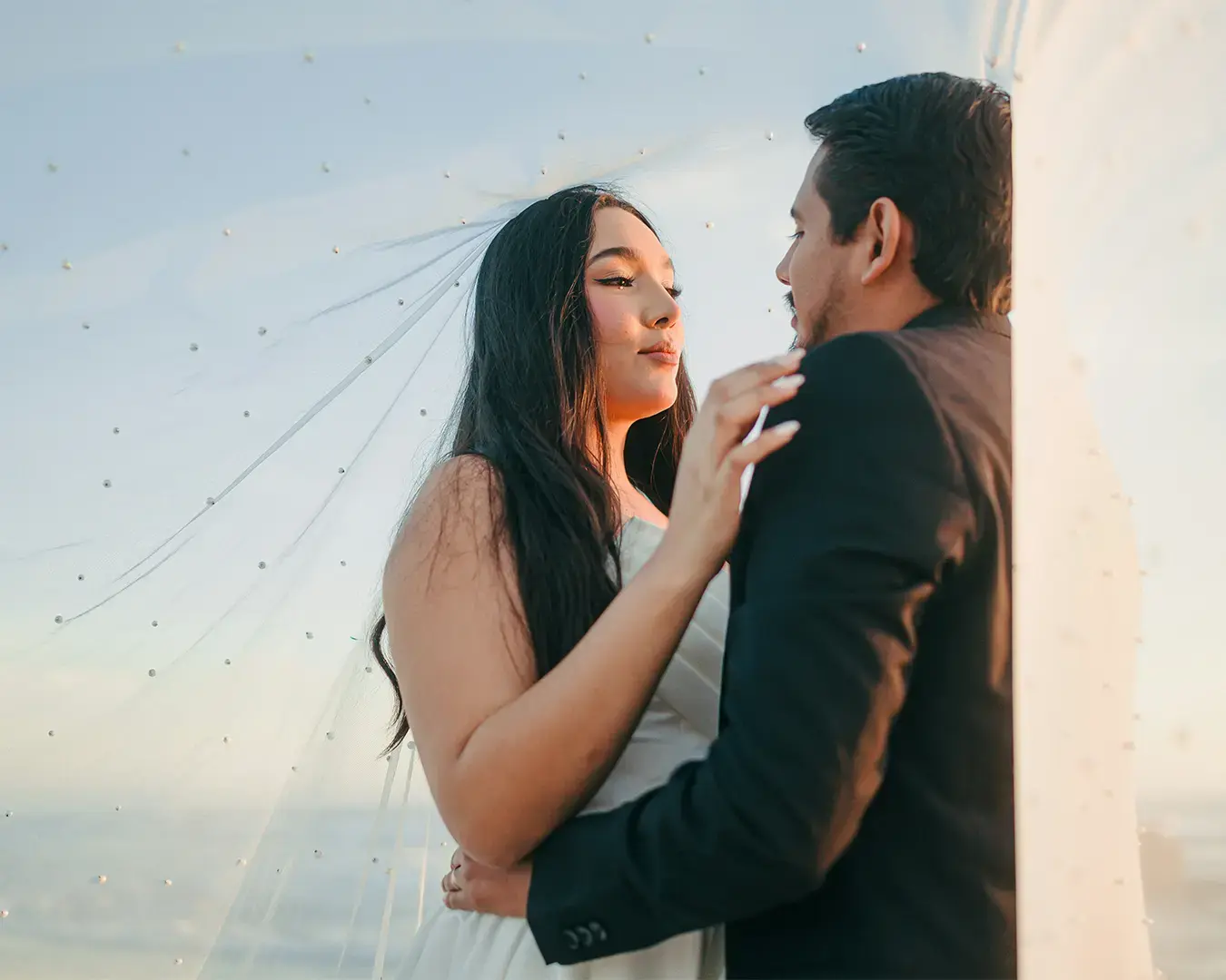 A loving couple stands together at sunset, framed by a colorful sky, symbolizing romance and connection.