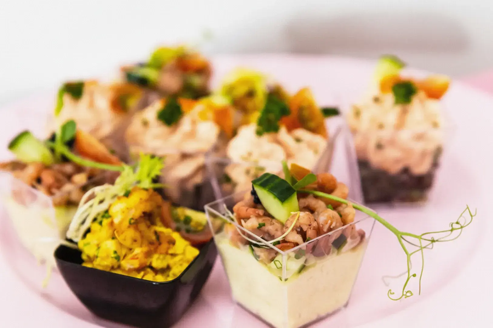 Assorted small plated dishes on a pink table with a soft, bright background.