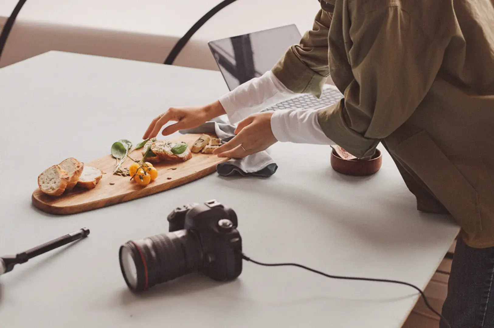 Hands styling figs, bread, and small bowls on a wooden board.