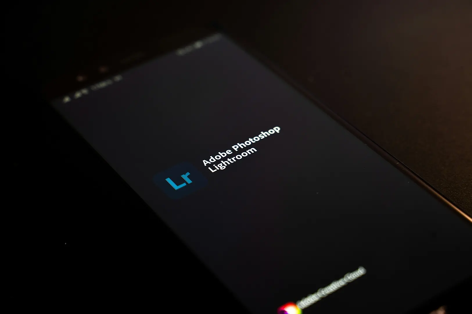Smartphone screen displaying the Adobe Photoshop Lightroom app logo on a dark background.