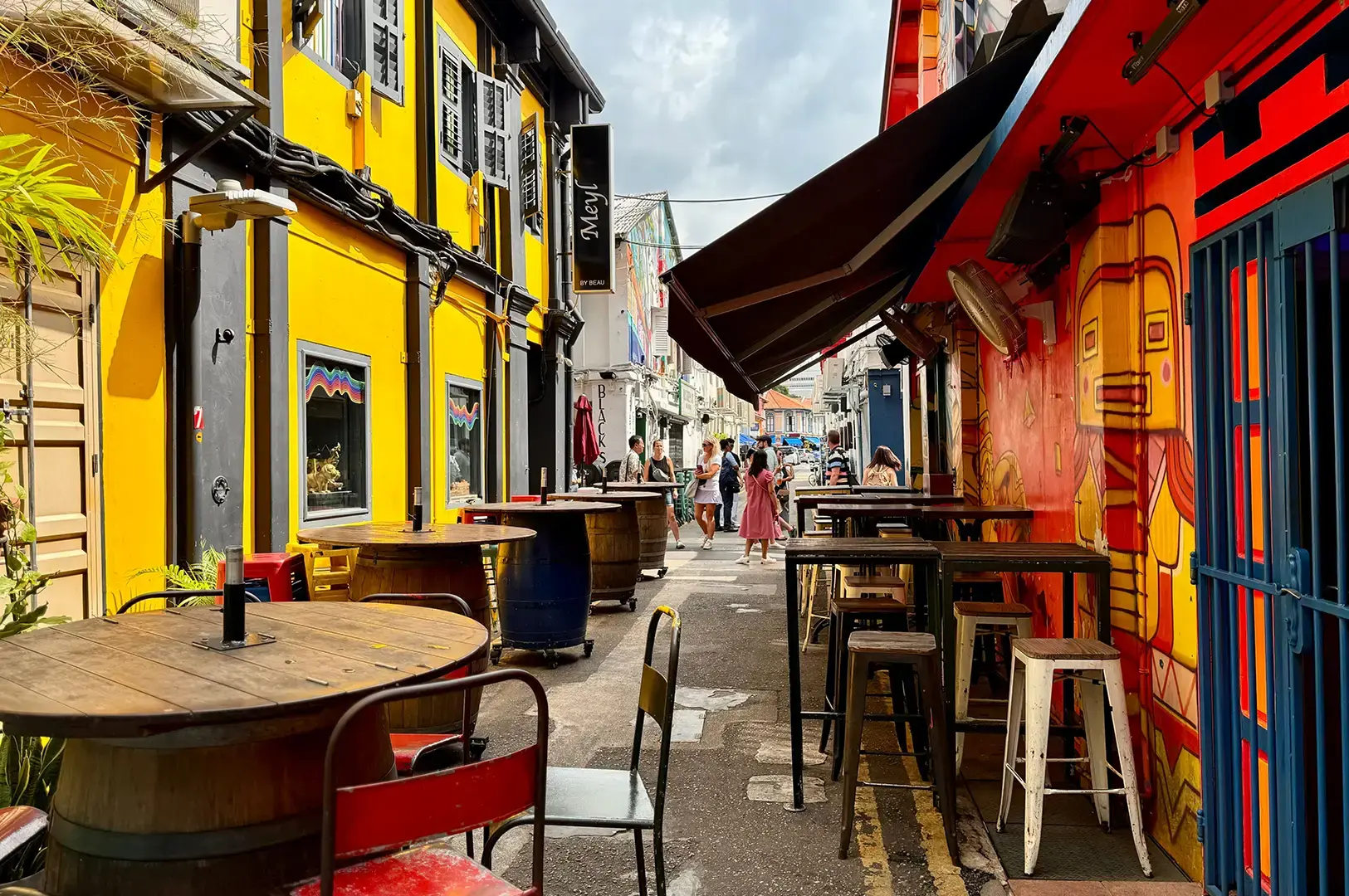 Haji Lane with bright shophouse walls, outdoor tables, and a narrow pedestrian lane.