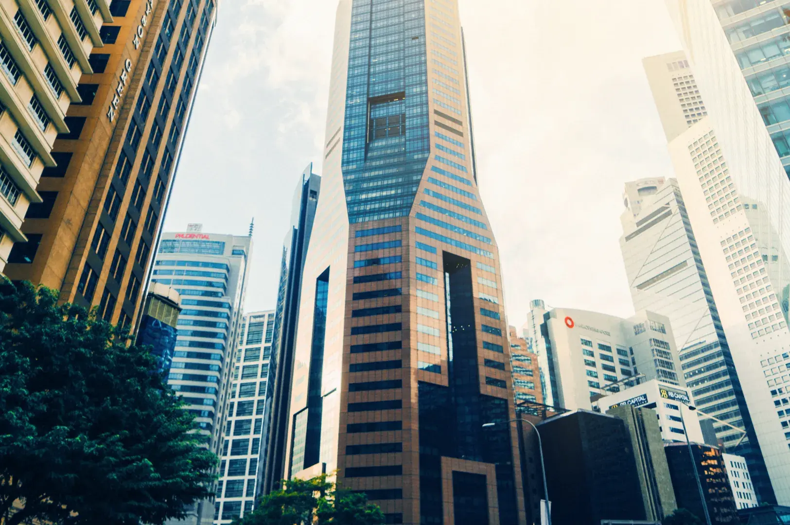 A low-angle view of modern skyscrapers with glass and metallic facades against a bright sky.
