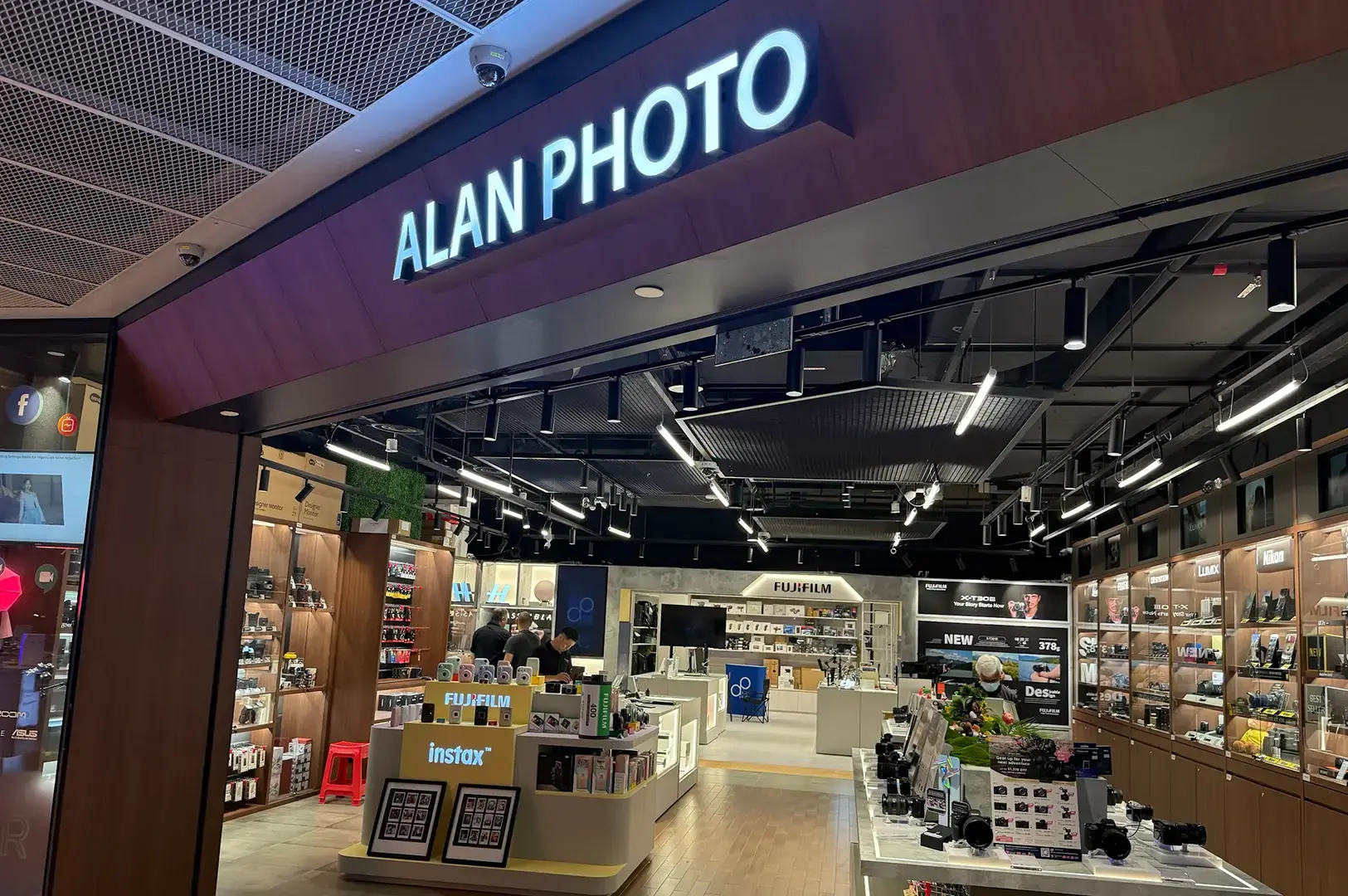 Alan Photo storefront showing a bright camera shop interior with Fujifilm products, Instax displays, cameras, and accessories.